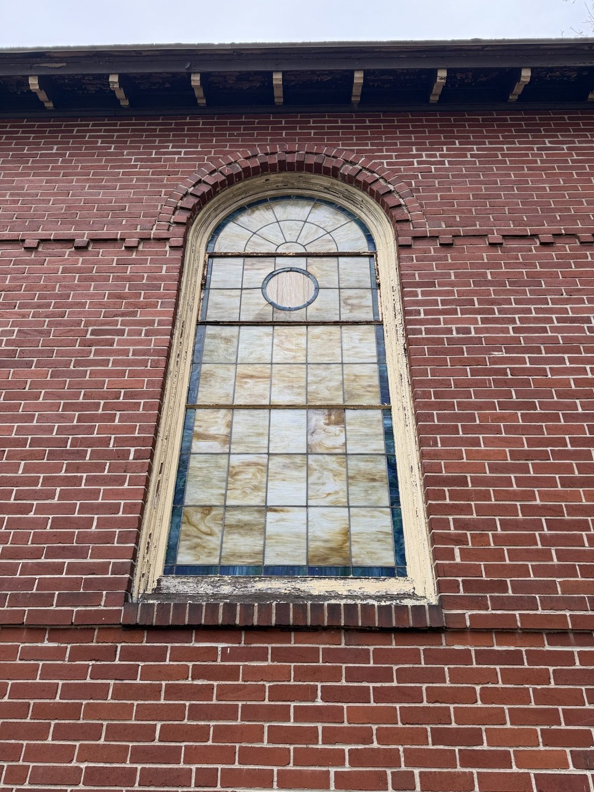 An arched stained glass window set in brick